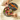 Two hands reach for assorted chocolates in a round, decorative box with a floral pattern and orange ribbon, placed on a light fabric surface. The box is filled with colorful, wrapped sweets. - AI generated text